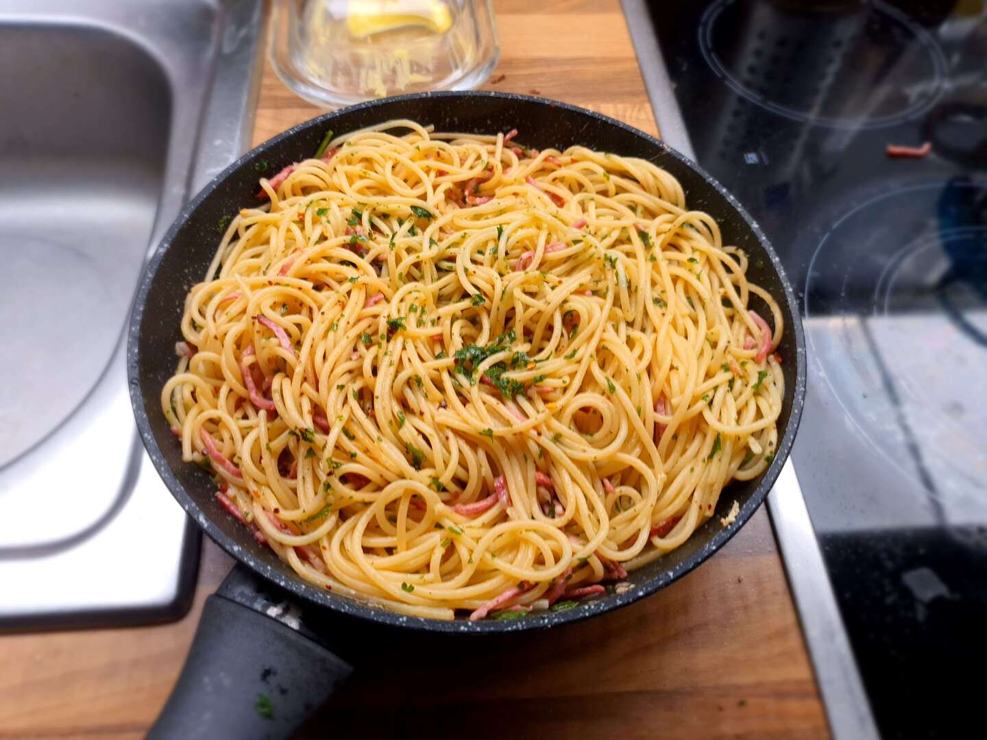 a photo of a pan that contains spaghetti with parsley and meat slices